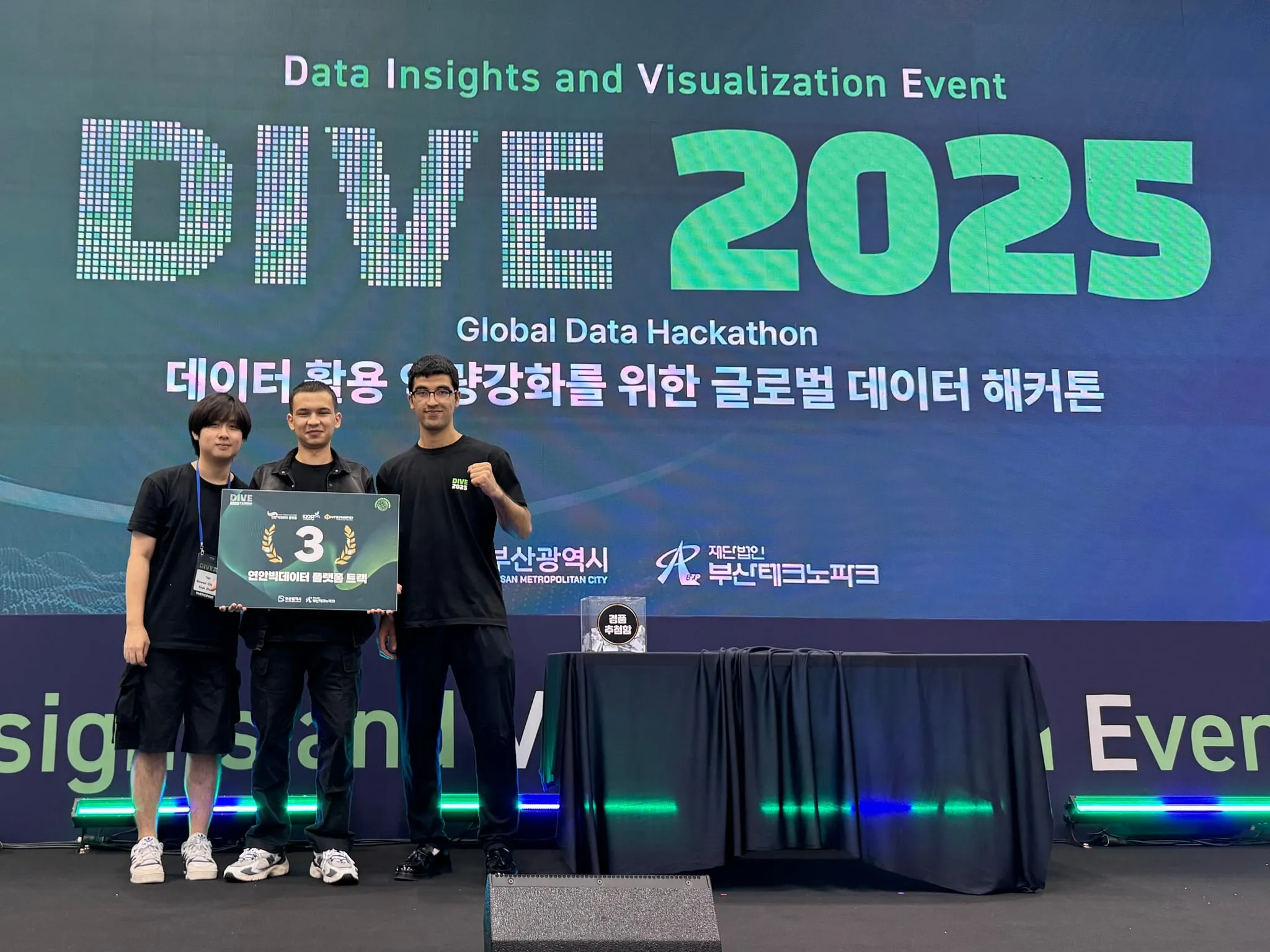 The three of us on stage at DIVE 2025 in Busan, holding the third-place sign for the coastal big data platform track.